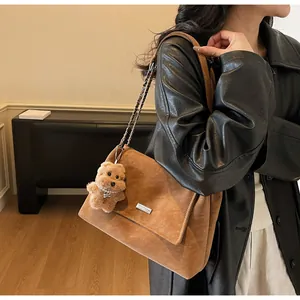 Detalle de bolso de ante marrón con colgante de cachorro de felpa y correa de cadena metal