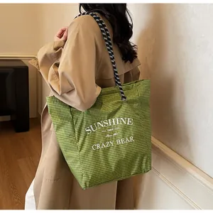 Close-up of green checkered canvas tote with woven rope handles and sunshine text print