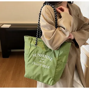 Detail of green checkered canvas tote bag with SUNSHINE print and thick rope strap