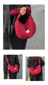 Detail of red heart-quilted nylon crossbody bag with wide padded shoulder strap
