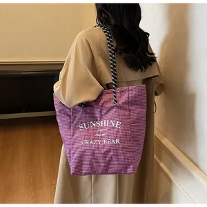 Detail of purple gingham tote bag with woven straps and graphic print on model