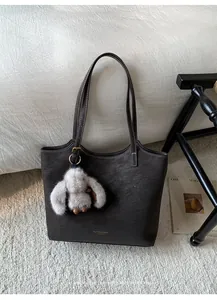 Detail of vintage large capacity leather tote bag with contrast stitching and rabbit charm