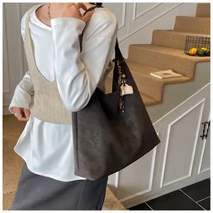 Detail of dark coffee shoulder bag featuring matte leather and a coffee cup charm