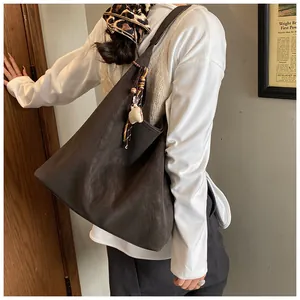 Detail of dark brown vintage faux suede tote bag with decorative beaded charm on shoulder