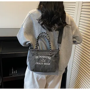 Detail of checkered tote bag with woven handles and sunshine bear text on a model