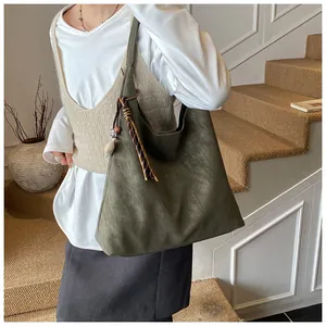 Detail of olive green tote bag featuring vintage matte texture and woven tassel charm