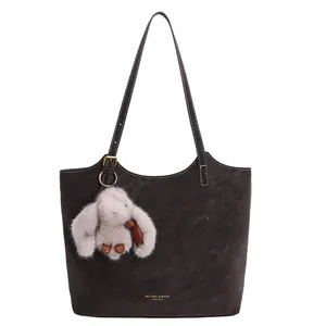 Large dark taupe leather tote bag with contrast stitching and a plush rabbit pendant