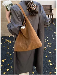Close-up of brown suede shoulder bag featuring a white COFFEE decorative charm on the handle