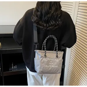 Gray checkered canvas tote bag worn by model, showing its large size and urban style