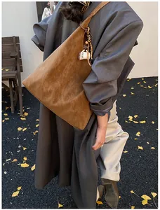 Detail of brown suede hobo bag with retro woven strap and coffee cup charm in autumn