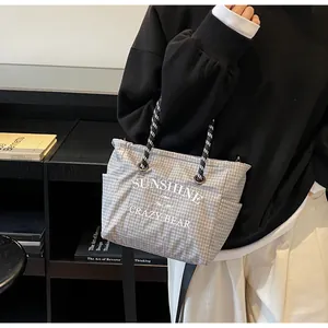 Detailed view of gray checkered tote bag with woven handles and printed text design