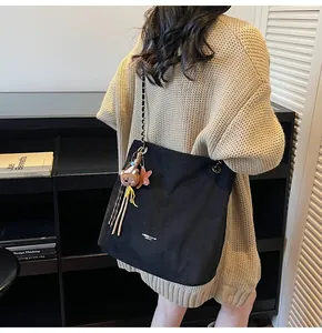 Detail of black tote bag with chain strap and cute bear charm decorations on model