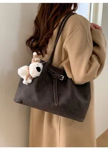 Dettaglio di una grande borsa tote in pelle scamosciata marrone con fibbia e ciondolo