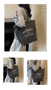 Detail of checkered canvas tote bag with woven straps and bold graphic lettering