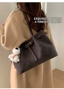 Dettaglio borsa tote vintage in pelle scamosciata marrone con fibbia e ciondolo peluche