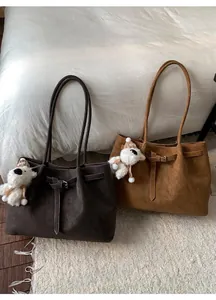 Dettagli di borse tote in camoscio marrone scuro con graziosi ciondoli a forma di pecora