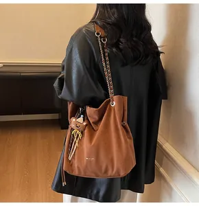 Detail of dark brown suede shoulder bag with gold chain strap and cute bear charm pendant