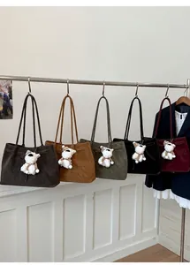 Dettaglio di borse tote in camoscio in cinque colori con ciondoli a forma di cucciolo