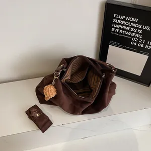 Deep brown matte leather tote bag with striped lining and plush charm in high-angle view
