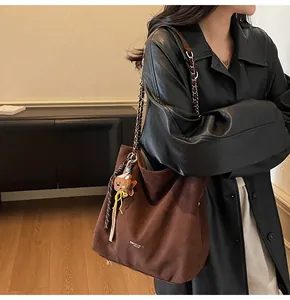 Detail of dark brown suede hobo bag featuring chain strap and cute bear charm accessory