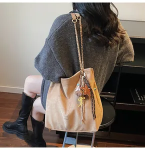 Detail view of camel suede tote bag with woven chain strap and star charms in home setting
