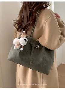 Dettaglio della borsa Boston in camoscio verde oliva con ciondolo a cane sul cappotto