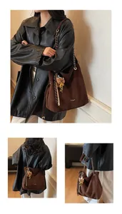 Detailed view of large dark brown suede tote bag with chain strap and teddy bear charm