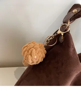 Detailed macro of a handmade light brown plush woven pendant with strawberry charm