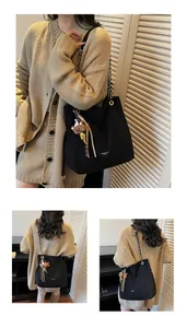 Detail of black tote bag with metal chain strap and cute bear charm for daily commute