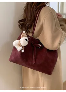 Dettaglio della borsa tote in pelle scamosciata bordeaux con fibbia e ciondolo