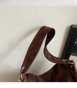 Close-up of wide suede strap and metal rivet details on dark brown tote bag