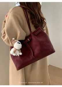 Dettaglio borsa tote bordeaux in pelle scamosciata con cinturino e ciondolo