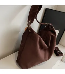 Detail of brown suede tote bag featuring soft folds and gold metallic buckle accents