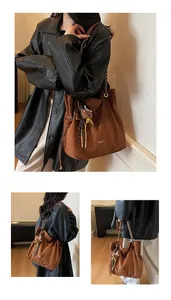 Detail view of large brown suede tote bag with chain strap and cute bear charm