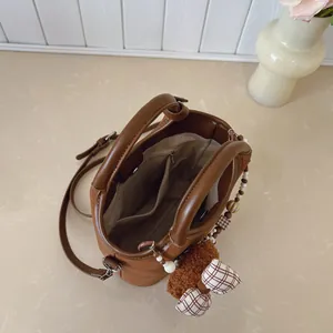 Dunkelbraune Perlen-Beuteltasche mit zwei Griffen und Umhängeband auf Marmorfläche