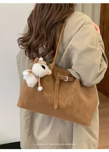 Dettaglio borsa vintage in pelle scamosciata marrone con ciondolo a pecora e fibbia