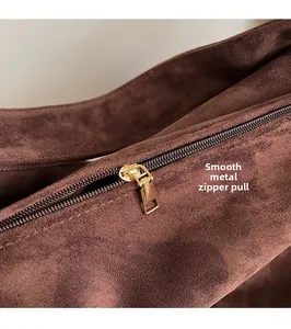 Close-up of golden hardware zipper pull on dark brown suede tote bag details