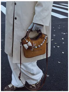 Nahaufnahme der braunen Wildledertasche mit Perlenanhänger und karierter Schleife