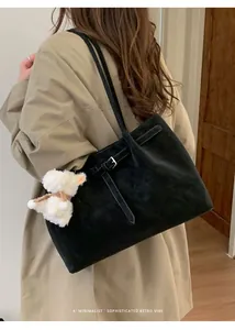 Dettaglio di una borsa tote vintage nera in pelle scamosciata con ciondolo a pecorella