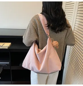 Close-up of pink oversized suede tote bag with woven knot charm and wide shoulder strap