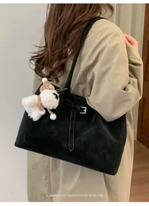 Dettaglio borsa tote in pelle scamosciata nera con ciondolo a forma di cucciolo e fibbia