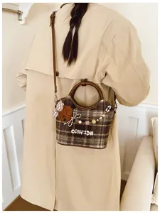 Detail einer Vintage-Plaid-Tweedtasche mit Bärenanhänger und Perlenverzierungen