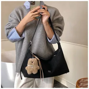 Detail of black matte moon bag with a cute brown bear charm and adjustable strap