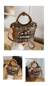 Detail der karierten Tweed-Tasche mit Plüschbären-Anhänger und Perlenverzierung