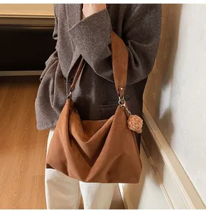 Close-up of caramel brown oversized tote bag with soft suede texture and floral charm
