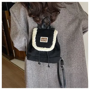 Detail of black drawstring backpack featuring faux shearling trim and brown bear patch