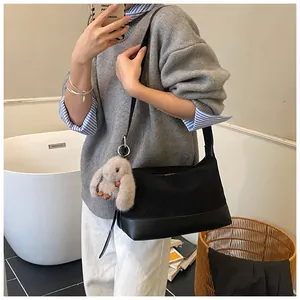 Detalle de bolso tote de nailon negro con un lindo llavero de conejo de peluche marrón