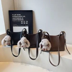Three colors of French vintage shoulder bags with plush rabbit charms on white steps