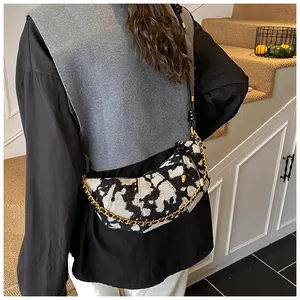 Detail of crescent bag with black and white jacquard pattern and gold chain strap