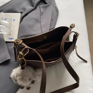 Brown vintage leather shoulder bag with interior compartments and plush charm